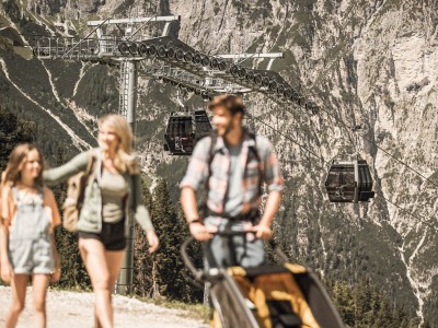 A man, a woman and a child out walking; behind them, you can see the cable cars from Ladurns