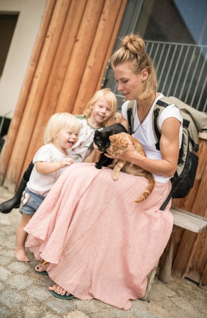 Eine Mama streichelt mit ihren Kindern zwei Babykätzchen.
