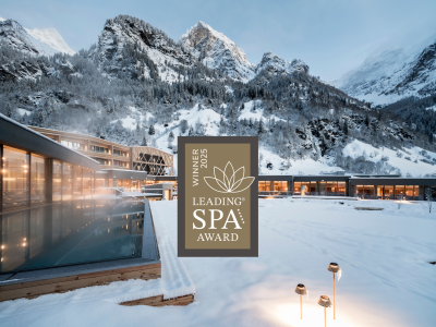 La piscina esterna del Feuerstein nella neve e il logo Leading Spa Award Winner 2025.