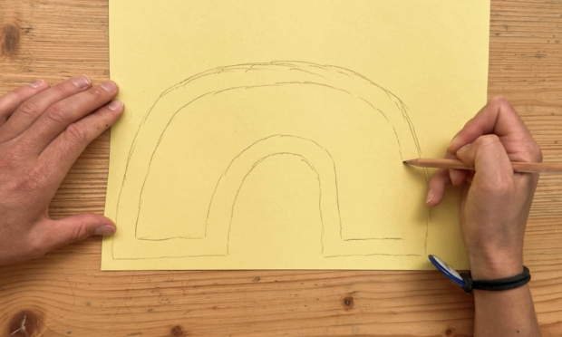 A rainbow is drawn on thick paper to be cut out.