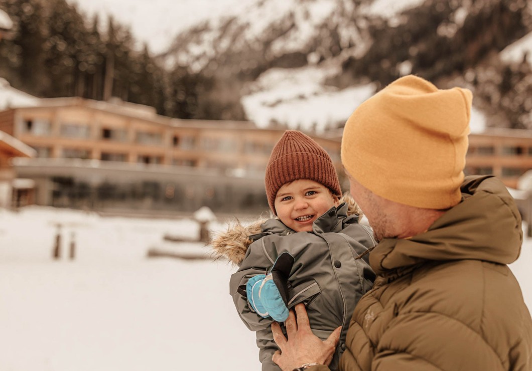 Father holding his child in front of the hotel in winter