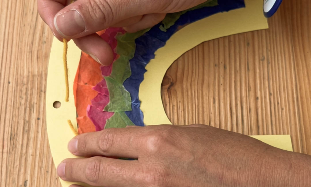 A piece of string is threaded through a small hole and tied at the end so that it can then be hung up.