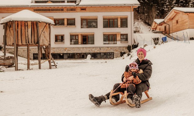 Madre e figlia scendono con la slitta lungo la collina nel giardino del Feuerstein.