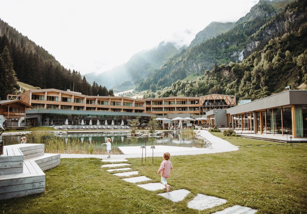 The sun is shining and we can see the swimming pond and, behind it, the Feuerstein Nature Family Resort.