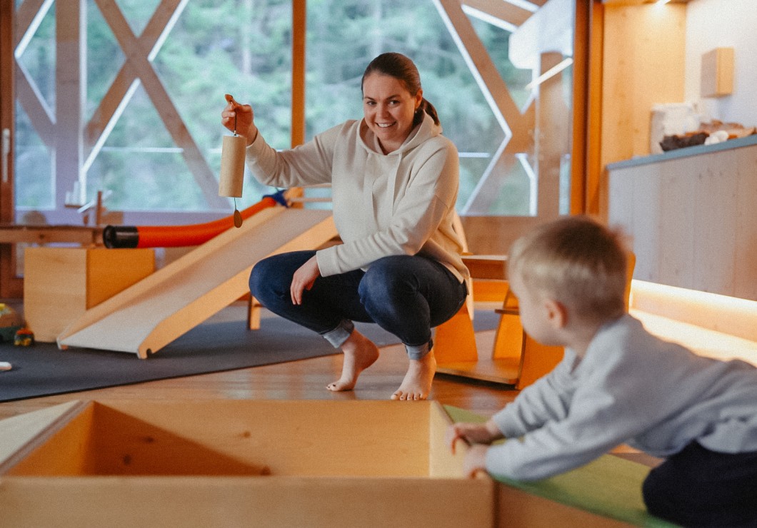 Saskia picks up a toy and shows it to a toddler.