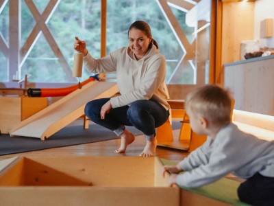 Saskia picks up a toy and shows it to a toddler.