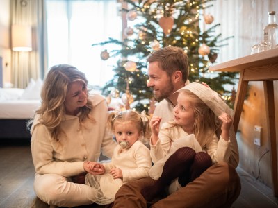 Famiglia seduta davanti all’albero di Natale in camera
