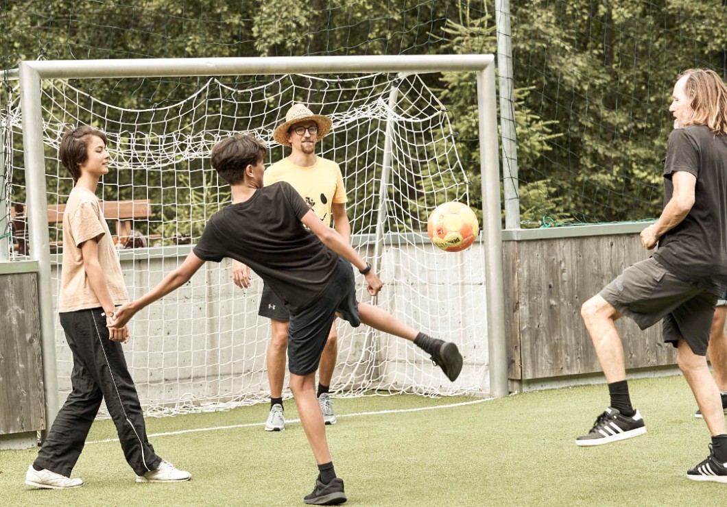 1 Mann mit 2 Jungs und Kinderbetreuer beim Fussballspielen