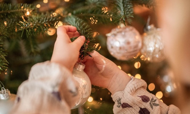A child hanging a Christmas bauble on the tree