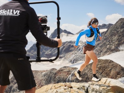 Severine is running along the rocks while being filmed by the cameraman.