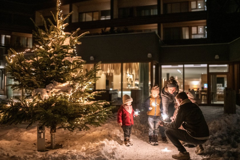 The family are standing in front of the house and in front of the Christmas tree, lighting a ‘Sternspritzer’.