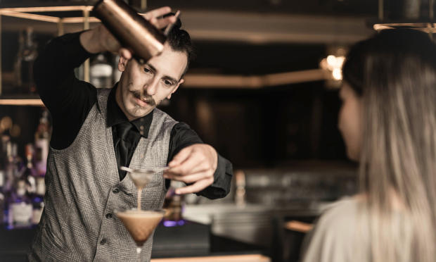 Der Barkeeper macht der Dame einen Cocktail.