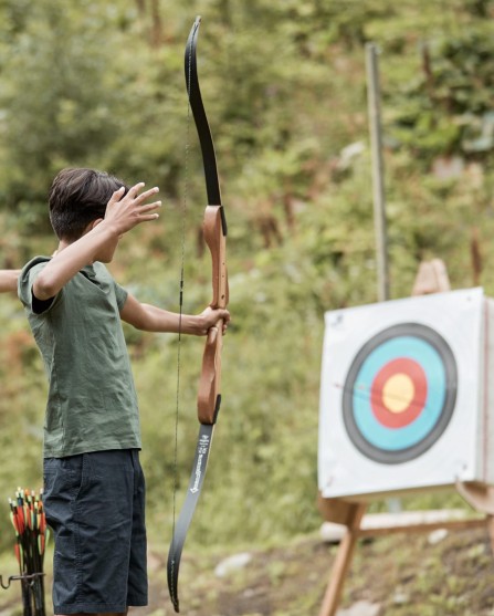 Un istruttore spiega a un adolescente come usare l'arco per il tiro con l'arco