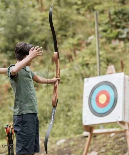 Un istruttore spiega a un adolescente come usare l'arco per il tiro con l'arco