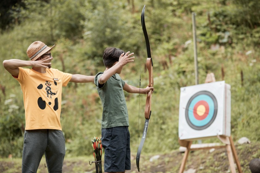 Un istruttore spiega a un adolescente come usare l'arco per il tiro con l'arco