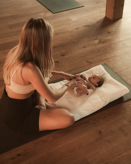 Mutter mit liegendem Baby im Yoga Raum