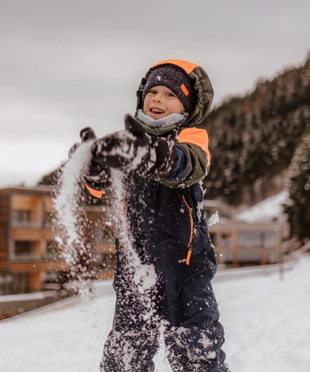 Bambino che gioca e lancia la neve all'aria in un paesaggio invernale