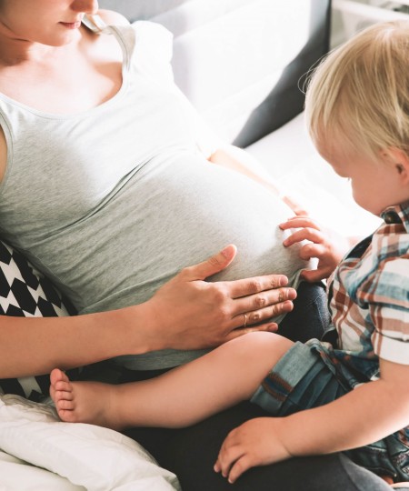 Kleiner Junge begutachtet den schwangeren Bauch seiner Mutter