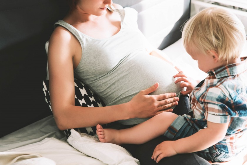 Kleiner Junge begutachtet den schwangeren Bauch seiner Mutter