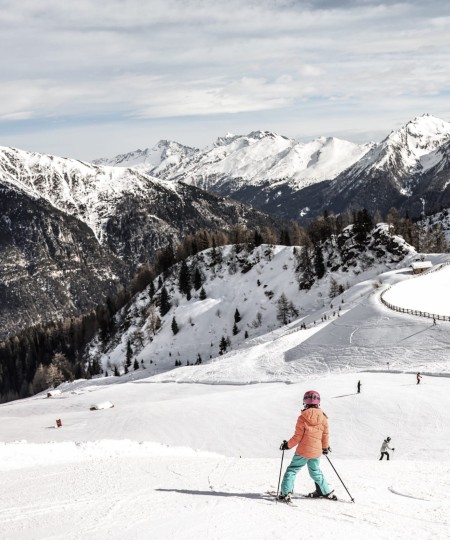 Ragazza che scende con gli sci su una pista innevata in montagna
