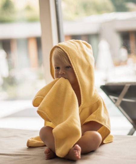 Bambino piccolo seduto con un accappatoio giallo