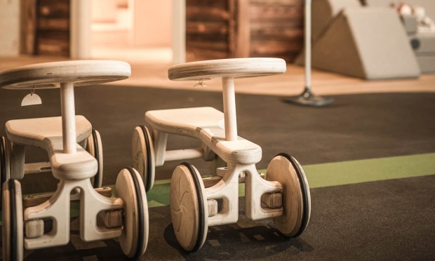 2 macchinine di legno davanti a una casa delle bambole accessibile