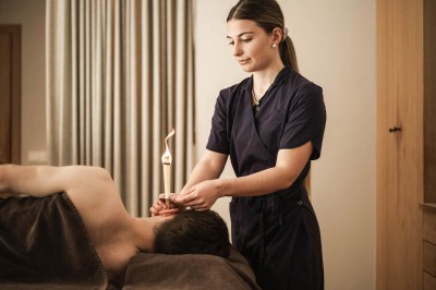 Una terapeuta utilizza una candela auricolare nell'orecchio di una persona sdraiata