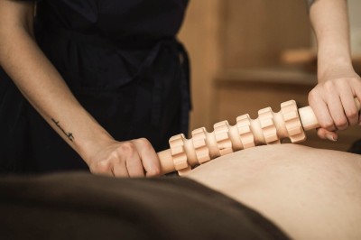 Mani che fanno scorrere un rullo di legno sulla schiena per massaggio