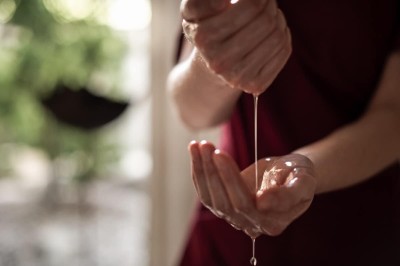 Mani che fanno colare olio nella mano per un trattamento corpo