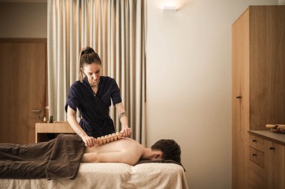 Terapeuta massaggia la schiena di una persona sdraiata con un rullo di legno