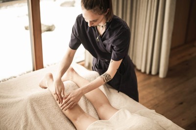 Terapeuta massaggia la gamba di una persona sdraiata su lettino