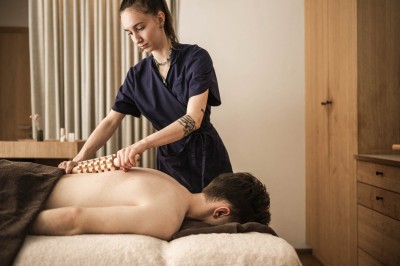 Donna che utilizza un rullo di legno sulla schiena di un cliente sdraiato