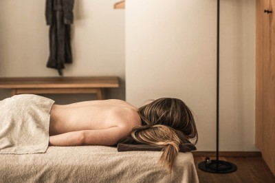 Una persona sdraiata a pancia in giù su un lettino da massaggio in una stanza