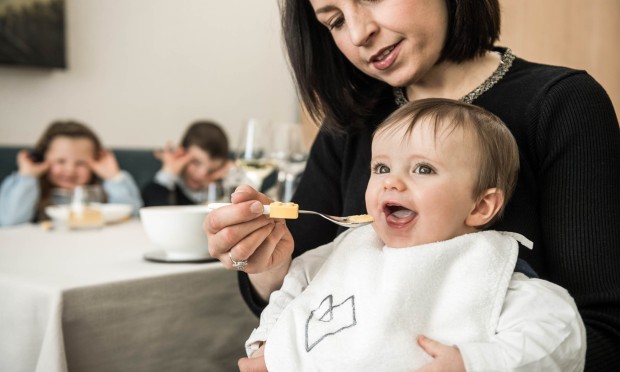 Una famiglia è seduta comodamente insieme, mentre un bambino tiene in mano una tazzina.