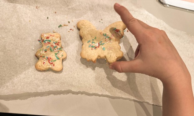 Mano che posiziona biscotti decorati su carta da forno.