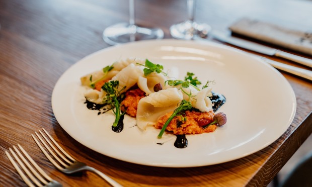 Piatto gourmet impiattato con ingredienti raffinati e presentazione curata