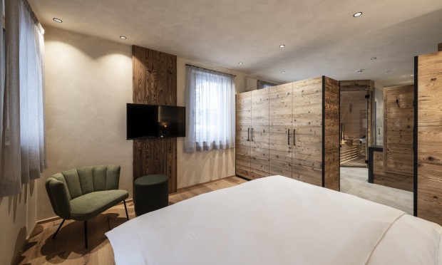 Una camera elegante con dettagli in legno, letto grande e zona salotto