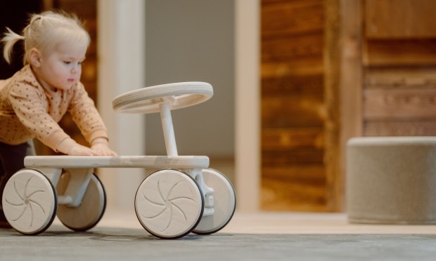 Bambino piccolo gioca con un'automobilina di legno