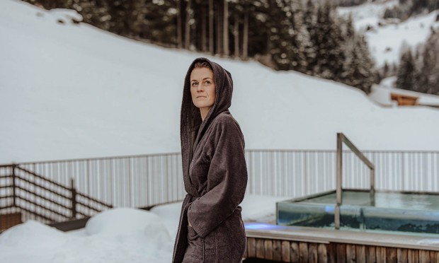 Frau in Bademantel auf Dachterasse im Winter