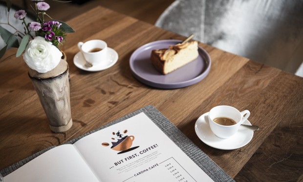 Tavolino per la colazione con caffè, dolce, libro e fiore decorativo