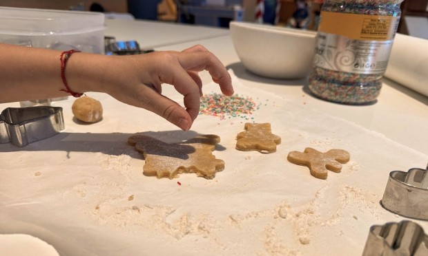 Bambino che taglia sagome di biscotti sulla pasta infarinata con formine.