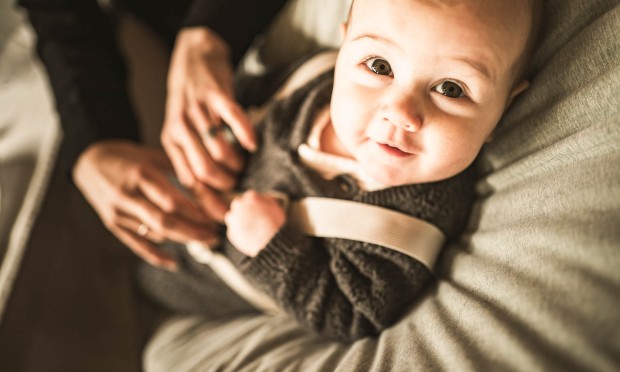 Un bambino guarda incuriosito nella fotocamera mentre viene tenuto in braccio.