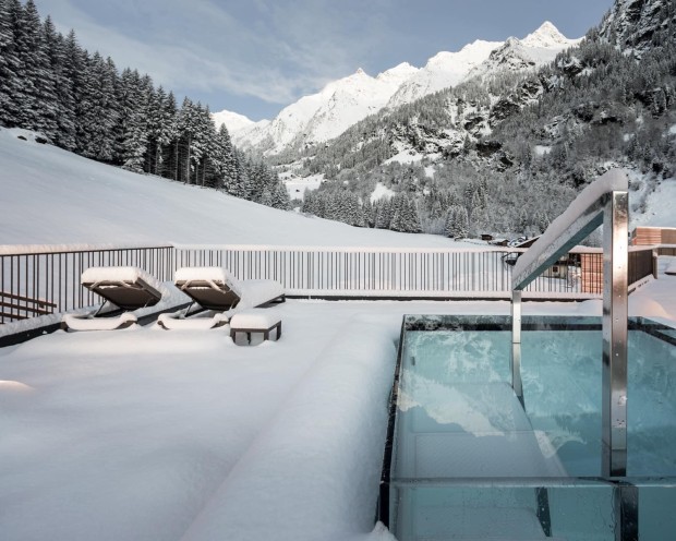Vista su terrazza con vasca idromassaggio e sdraio sulla neve e montagne