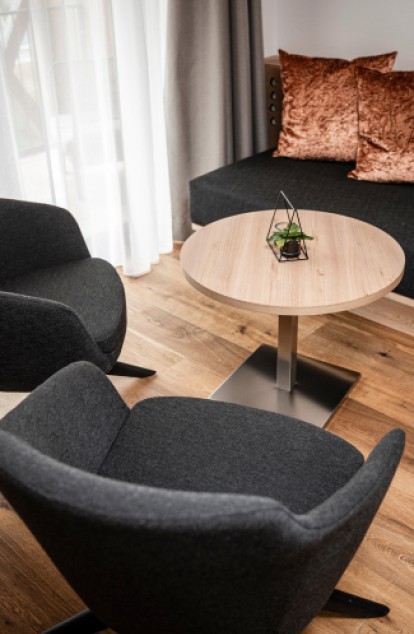 A cozy lounge area with black chairs and a wooden table in a modern setting.