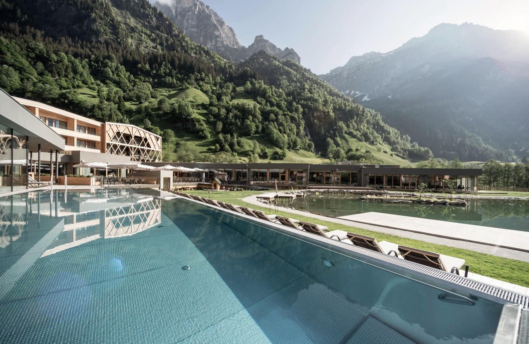 Piscina all’aperto presso il complesso alberghiero con vista sulle montagne dell’Alto Adige presso il Wellness Family Hotel South Tyrol.