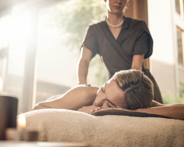 Una donna si sta godendo un massaggio alla schiena presso l'hotel benessere per famiglie in Alto Adige.