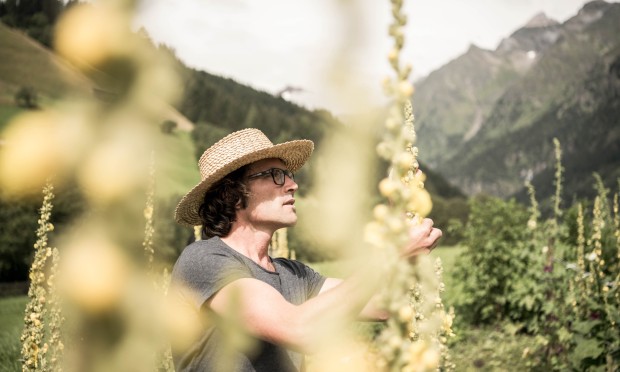 A man in a wide hat stands among the herbs and enjoys the sun.