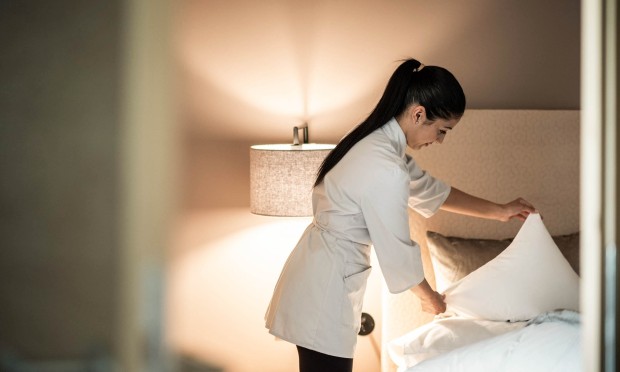 Cameriera del Feuerstein rifà il letto sistemando i cuscini in una stanza elegante.