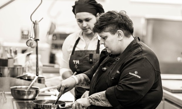 Chef tatuato del Feuerstein prepara un piatto con una collega assistente nella cucina del resort.