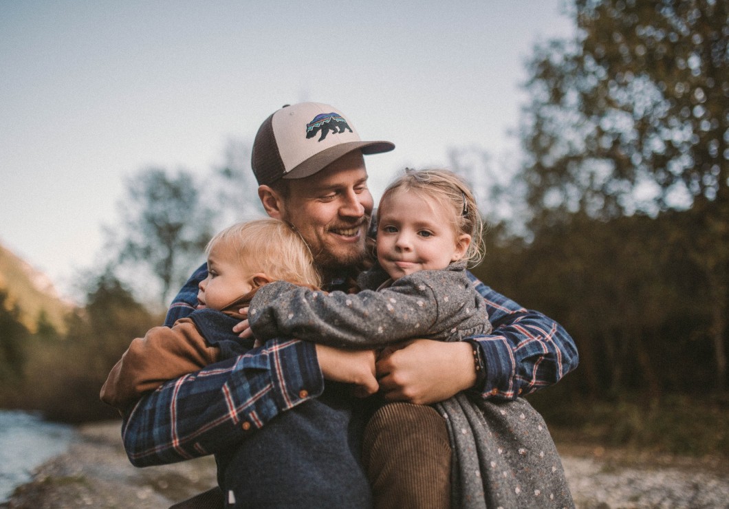 Un padre tiene i suoi bambini tra le braccia accanto al ruscello del Feuerstein.